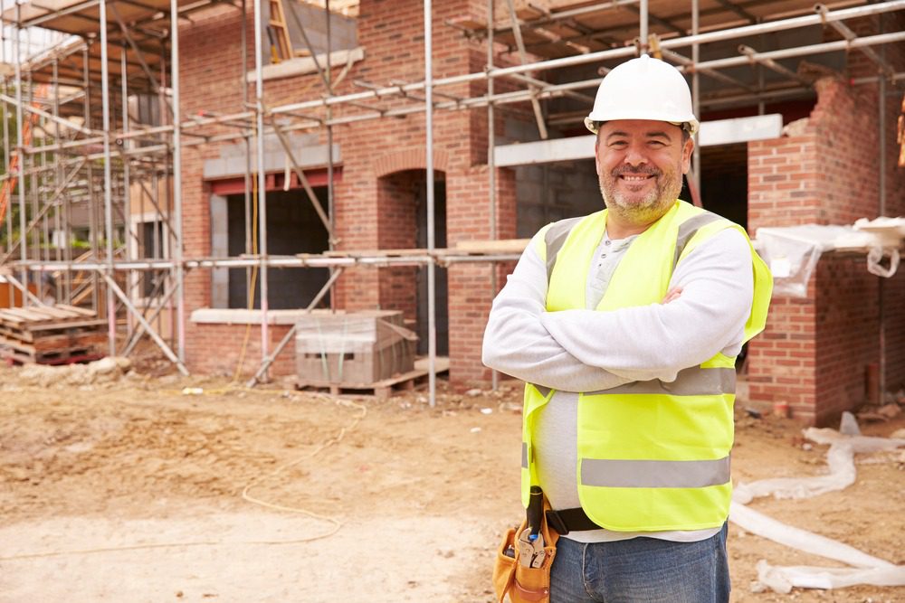 Smiling worker standing next to a construction site.