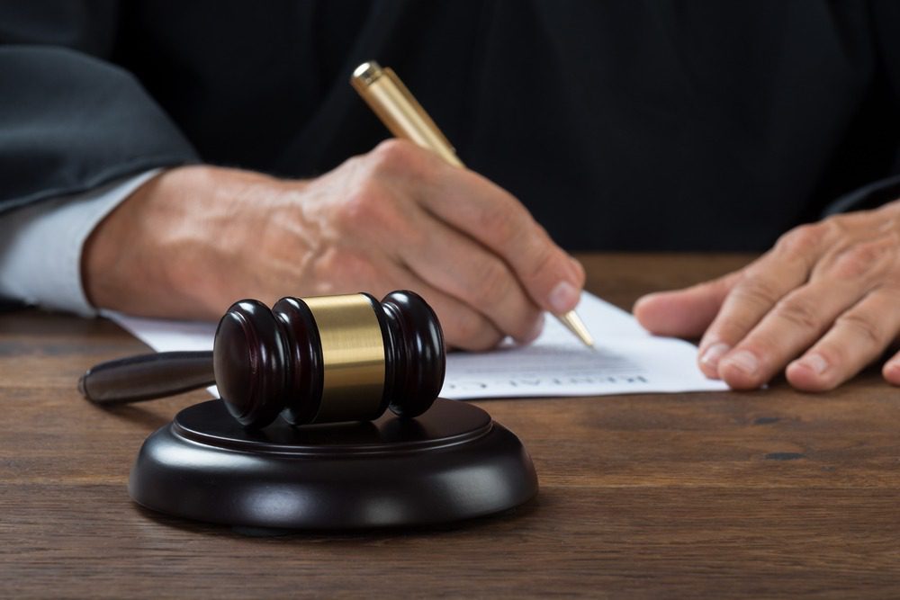 Lawyer signing documents with a golden pen.