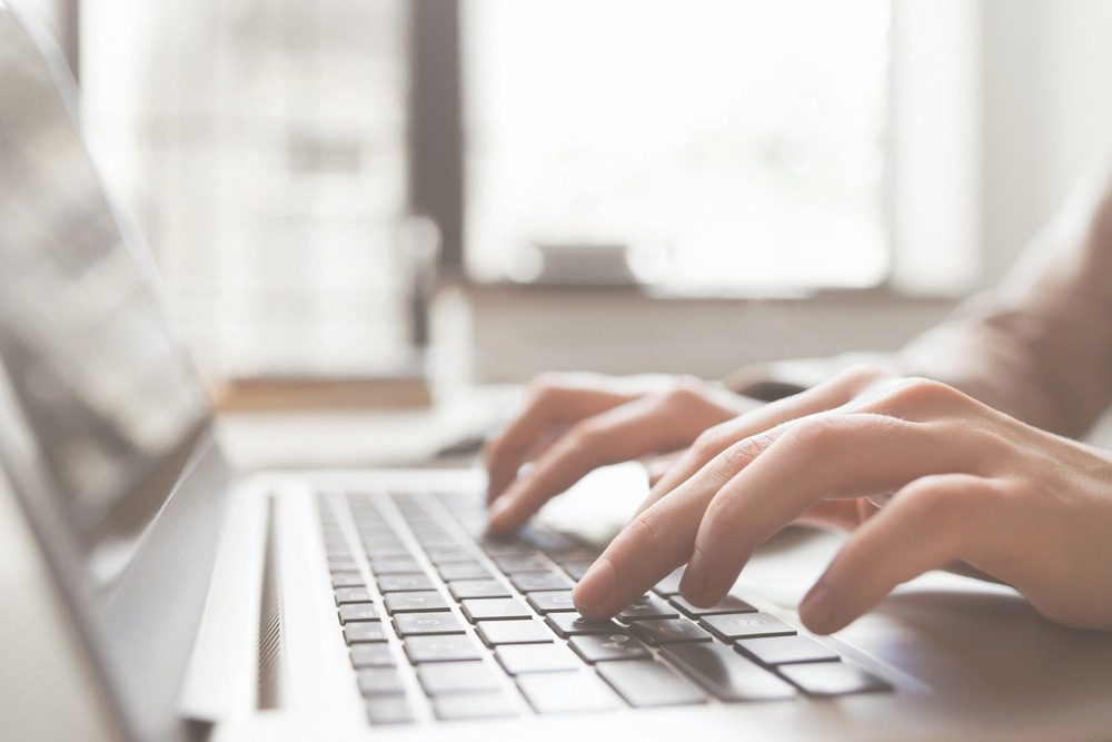 Person typing on a laptop keyboard.