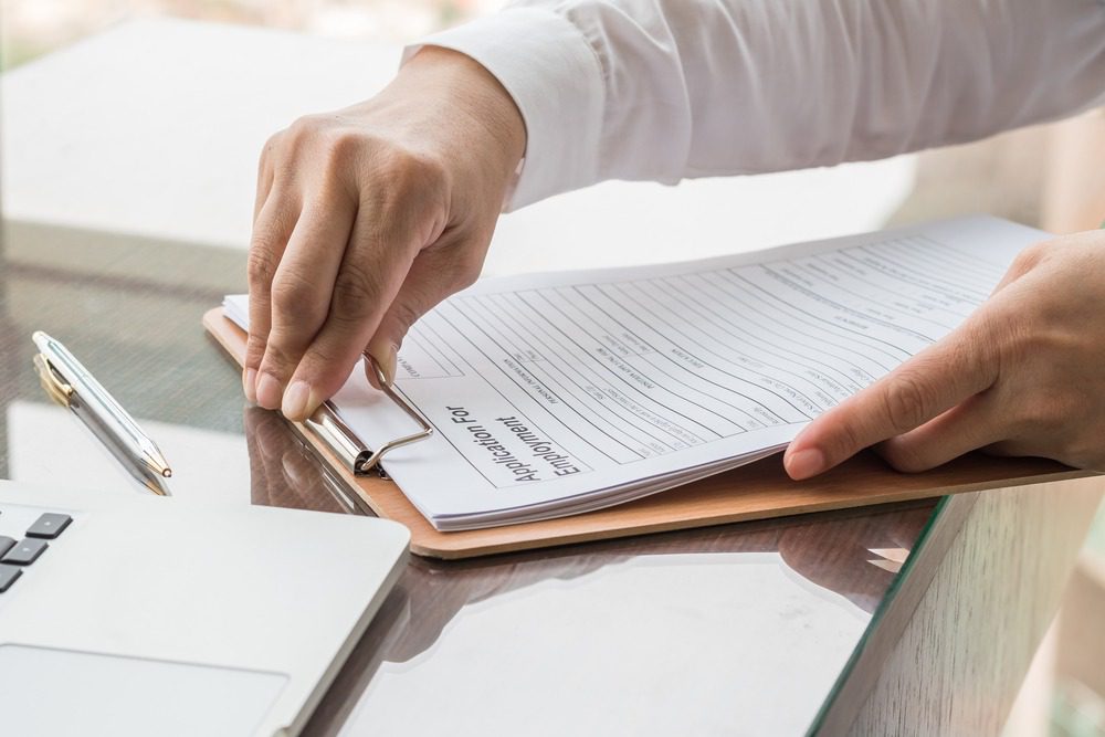 Man holding a clipboard with employment papers.