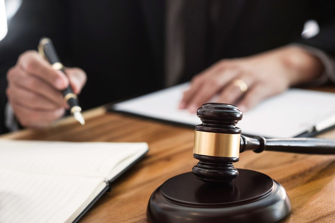 A disabilities Court Judge in robes signing a document.