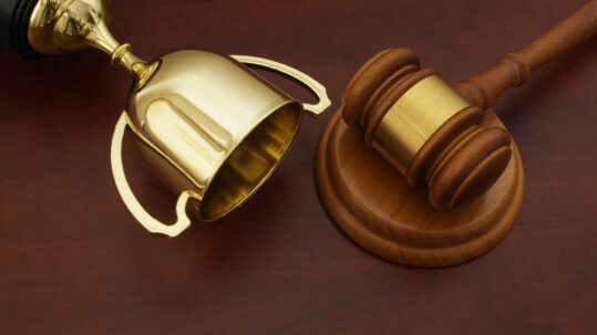 A law gavel with a golden trophy.