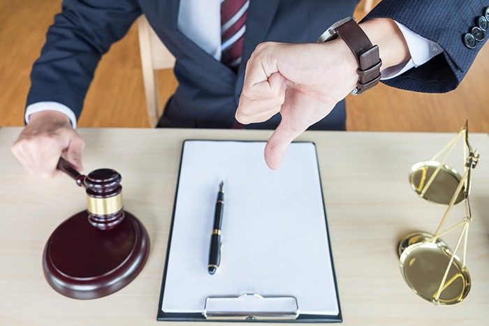 A lawyer giving a thumbs down as he smacks down his gavel.