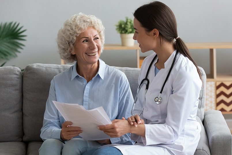 A doctor going through paperwork with a patient in-home.