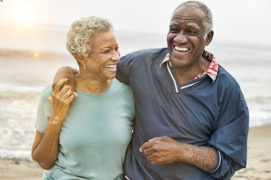 Older couple walking arm-in-arm on the beach.